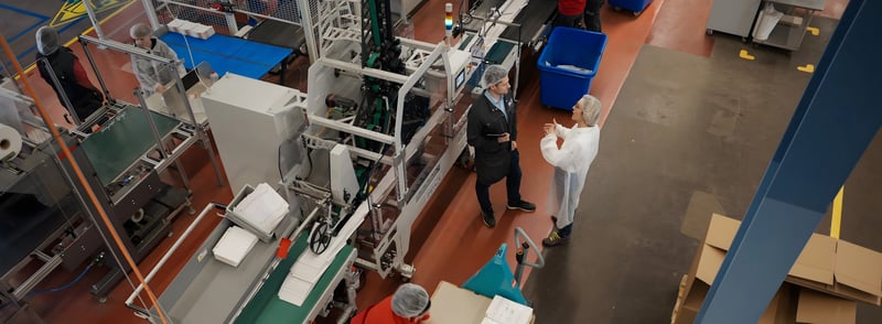 Natascha and Remo standing next to a folder-gluer equipt with an IMPACK ERGOSA packer and MFA Batch inverter 