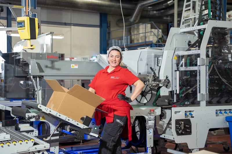 A woman stands at the automatic tilt table of the ERGOSA. A case is on the tilt table. 