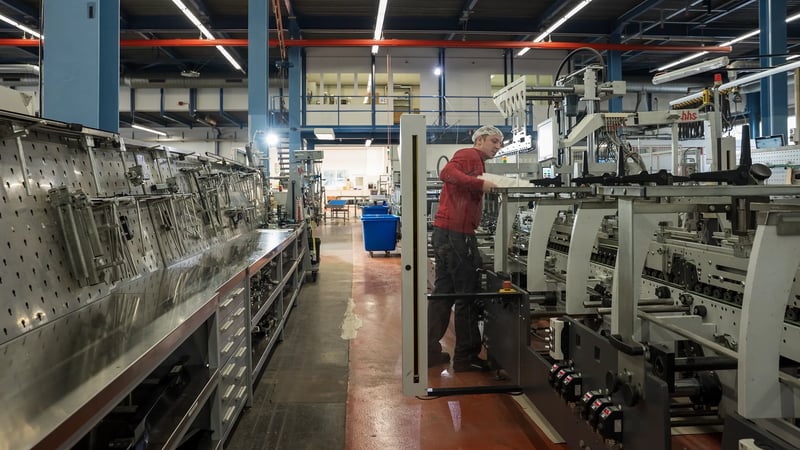 A man inspects a folder-gluer.